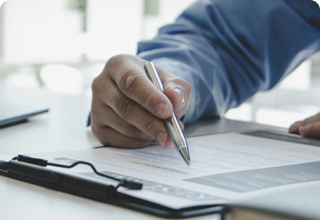 Man's Hand Signing Documents on a Clipboard